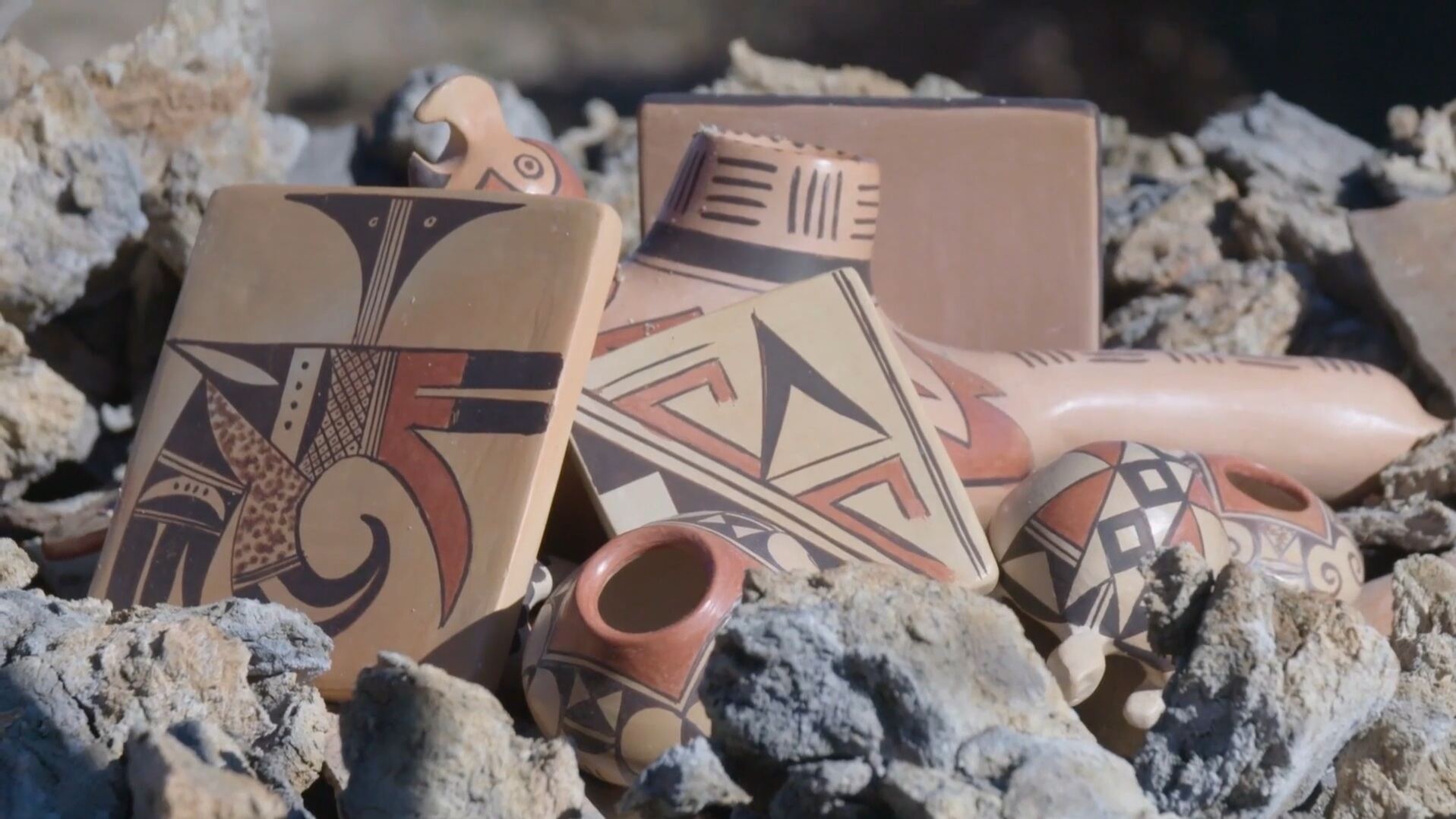 Painted pottery pieces stacked among rocks